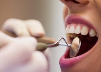 Close-up of dentist examining a female patient with tools at dental clinic