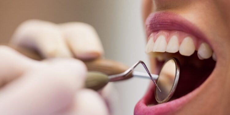 Close-up of dentist examining a female patient with tools at dental clinic