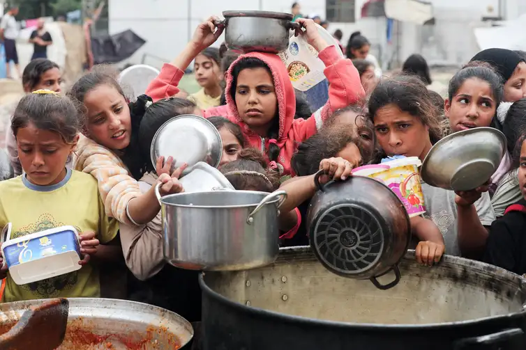 Palestinos aguardam para receber comida preparada por uma cozinha comunitária, em Nuseirat, Faixa de Gaza  08/04/2025  REUTERS/Ramadan Abed